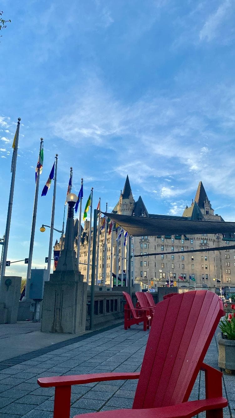 Red Muskoka chair facing the Chateau Laurier